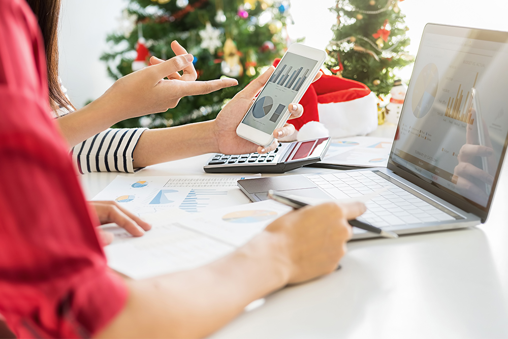 Two women looking at business reports with holiday decorations in the background